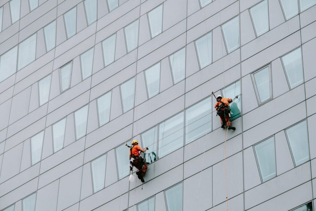 pexels-photo-12040693 Two Male Rope Access Workers Washing the Windows of a Modern Building